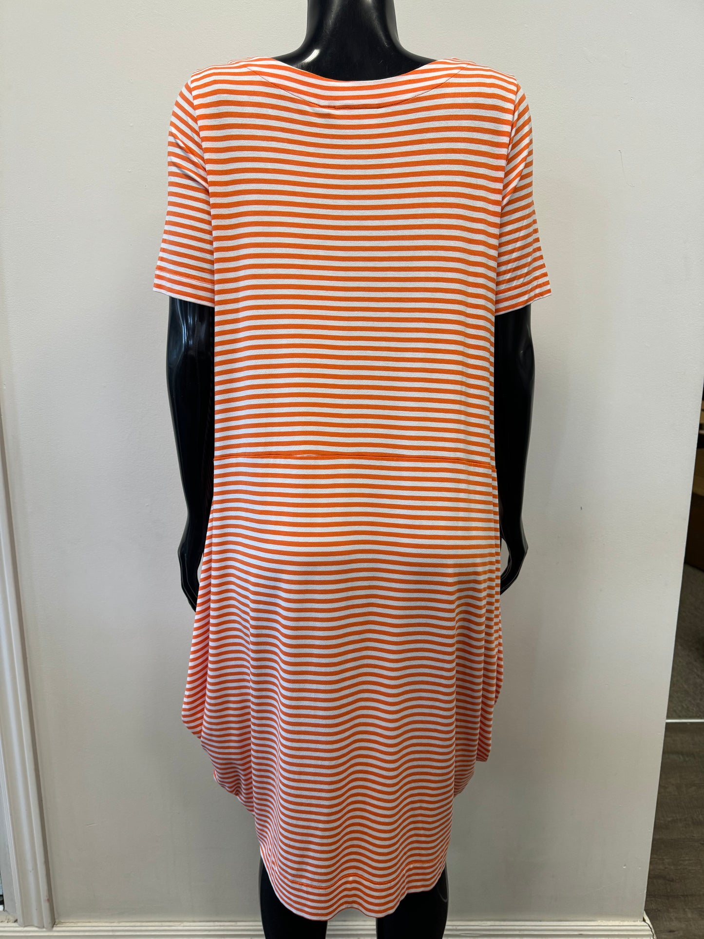 A mannequin is dressed in the versatile and comfortable FOIL Time Square Dress Shirt - FO6874, which features horizontal orange and white stripes. The dress shirt has a flowing, asymmetrical hemline and hangs loosely at the sides. The mannequin is positioned against a plain, white background.