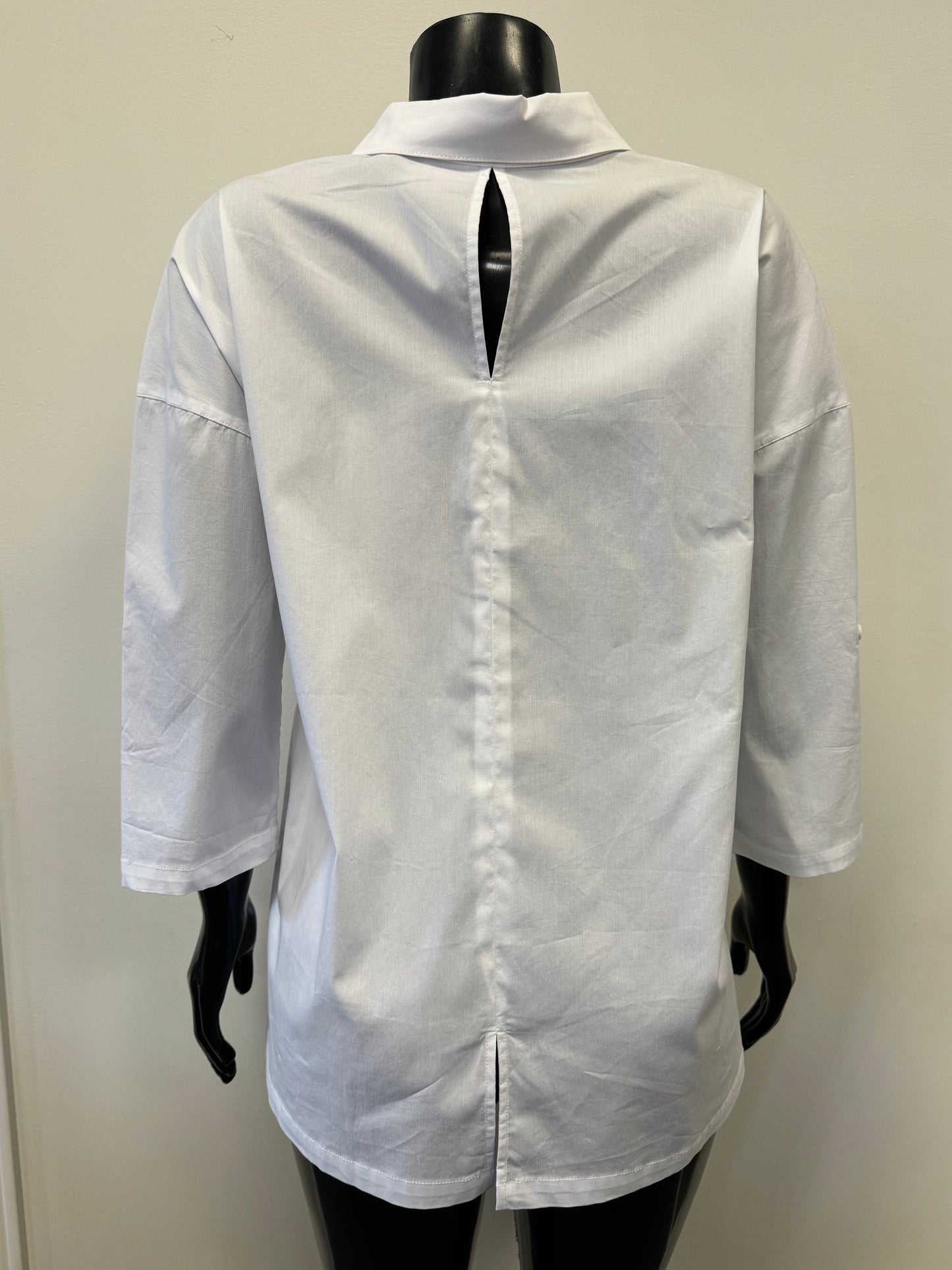 A plain white, long-sleeve FOIL Keeping Tabs Shirt (FO6936) from the FOIL brand is displayed on a black mannequin with a stand-up collar. The versatile shirt is unbuttoned at the top, featuring a relaxed fit and rolled sleeves, offering both comfort and a dressy look against a light-colored wall backdrop.