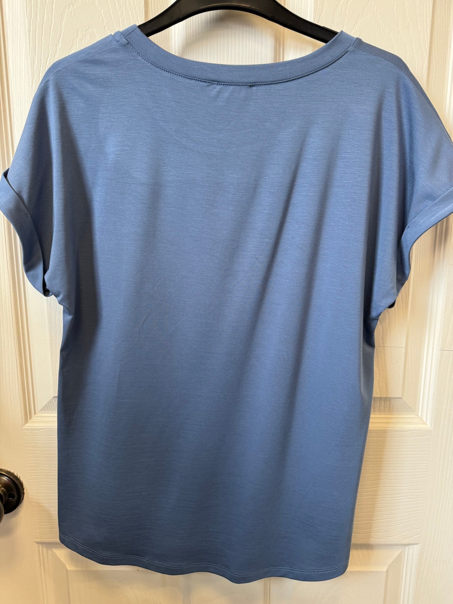 A Bali Crewneck T-Shirt - BLUE 8134 by Bali Corp hangs on a black hanger with the word "Bali" on it. The shirt, made in Canada, has a round neckline and is displayed against a white background, likely a door. The sleeves are rolled up slightly, and a small tag is visible at the neckline.