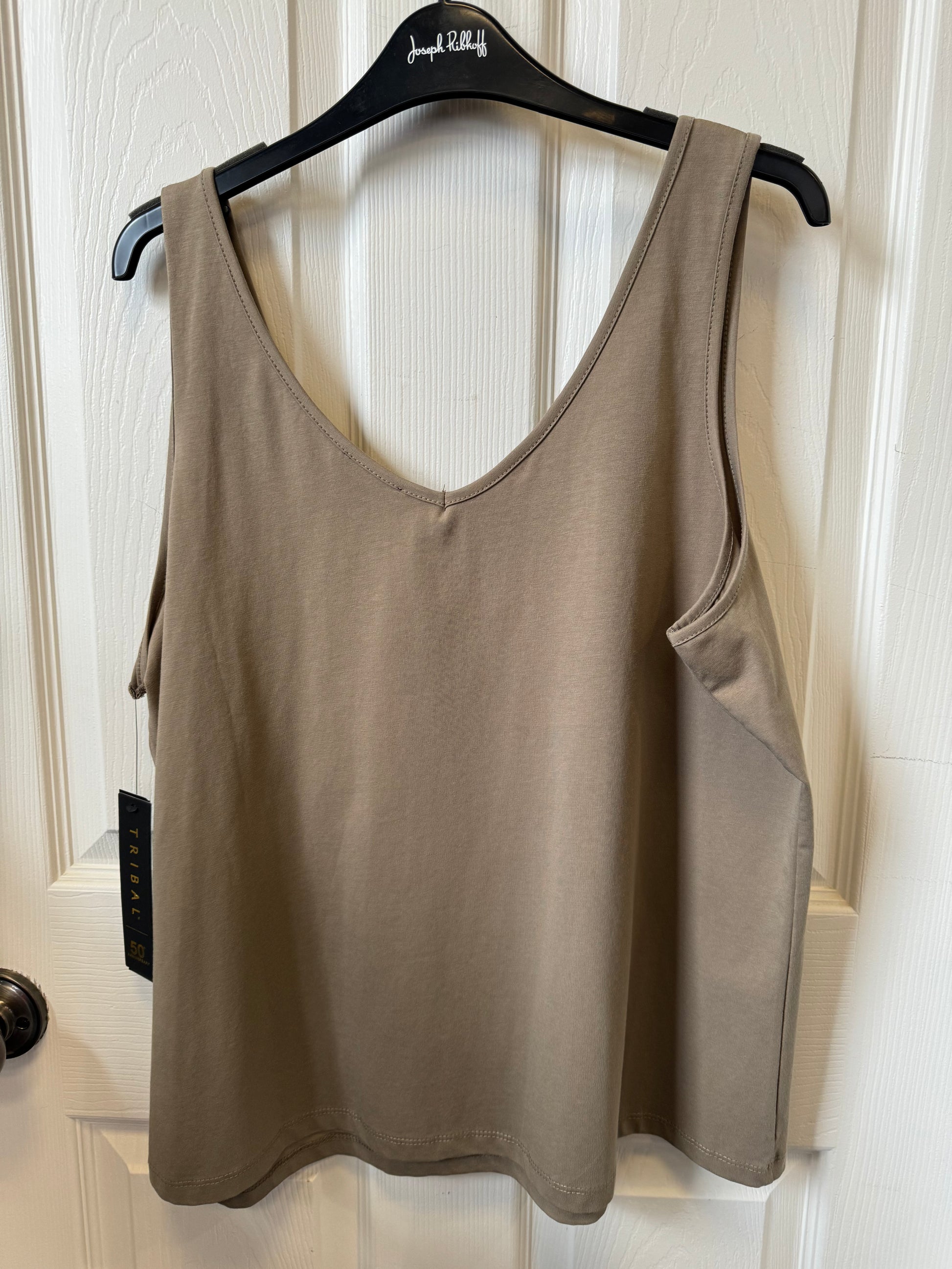 A chic, beige tank top—known as the Tribal Fern Tank Top (4820O-403-0407) from the brand Tribal—hangs elegantly on a black hanger against a white paneled door, perfect for any casual occasion.