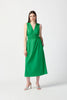 A woman stands against a plain, white background, wearing the Joseph Ribkoff Island Green Stretch Poplin Fit-and-Flare Dress 241127. This sleeveless, knee-length dress features woven fabric with gathered details at the waist. She has long, straight hair and is accessorized with drop earrings, bracelets, and open-toe high heels.