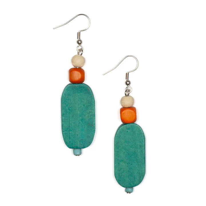 A pair of Wooden Lozenge Earrings - TURQUOISE by Suzie Blue, featuring a turquoise flat oval bead at the bottom, an orange cube bead in the middle, and a smaller cream-colored round bead at the top. These ethically sourced handmade earrings come with metal hooks for attachment.