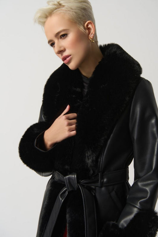 A person with short blonde hair wears the Black Leatherette Coat With Faux Fur Style 233927-Joseph Ribkoff by Joseph Ribkoff, tied at the waist with a matching belt. They have a thoughtful expression and are positioned against a plain gray background, epitomizing winter fashion at its finest.