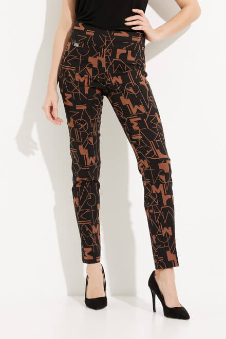 A person wearing the Abstract Print Straight Leg Pants Style 233279 by Joseph Ribkoff, featuring a black high-waisted design with an abstract brown geometric pattern, paired with a black top and black high heels, stands against a white background with one hand on their hip.