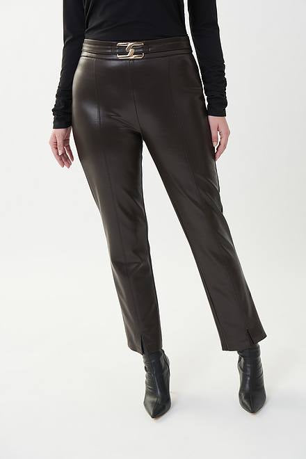 A woman stands against a plain white background, dressed in a black turtleneck sweater, Joseph Ribkoff's Style 223131 MOCHA faux leather pants featuring a metallic waist buckle, and black heeled boots. She has straight blonde hair and gazes directly at the camera with a neutral expression.