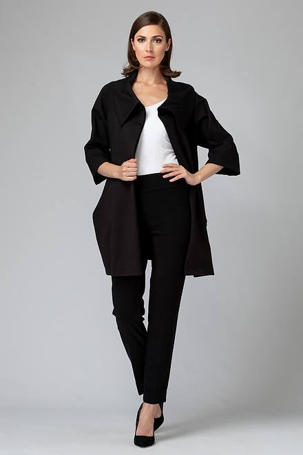 A person with shoulder-length brown hair is standing against a plain background, wearing a Joseph Ribkoff white top and black trousers. They are also sporting the Joseph Ribkoff Cowl Neck Coat Style 153302, which features three-quarter bell sleeves, along with black high-heeled shoes. One hand is resting on their hip while the other hangs relaxed by their side.