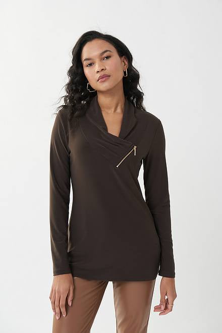 A woman with long, wavy hair is wearing a dark brown Joseph Ribkoff Zip Accent Tunic Style 223203 in mocha and light brown pants. She stands against a plain white background, looking confidently at the camera with her hands at her sides.