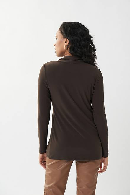 A woman with long, wavy hair is wearing a dark brown Joseph Ribkoff Zip Accent Tunic Style 223203 in mocha and light brown pants. She stands against a plain white background, looking confidently at the camera with her hands at her sides.