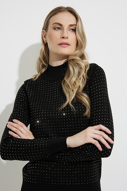 A woman with long, wavy blond hair stands against a plain white background. She is wearing a Joseph Ribkoff Embellished Mock Neck Style 224945 BLACK sweater paired with light brown pants. Her arms are crossed, and she has a neutral expression.