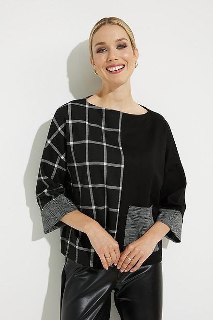 A woman stands against a white background wearing the Joseph Ribkoff Grid Print Top Style 224101, featuring a black and gray grid pattern on one side and a solid patch pocket. The top's relaxed fit complements her shiny black leather leggings and black heels. Her hair is tied back, and she smiles softly.