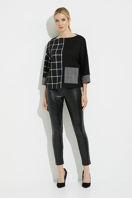 A woman stands against a white background wearing a stylish outfit. She is dressed in Joseph Ribkoff's Grid Print Top Style 224101, featuring a black base with gray plaid patterns on one side and a gray pocket, high neckline, and relaxed fit. She pairs it with black leather leggings and completes the look with black high-heeled shoes.