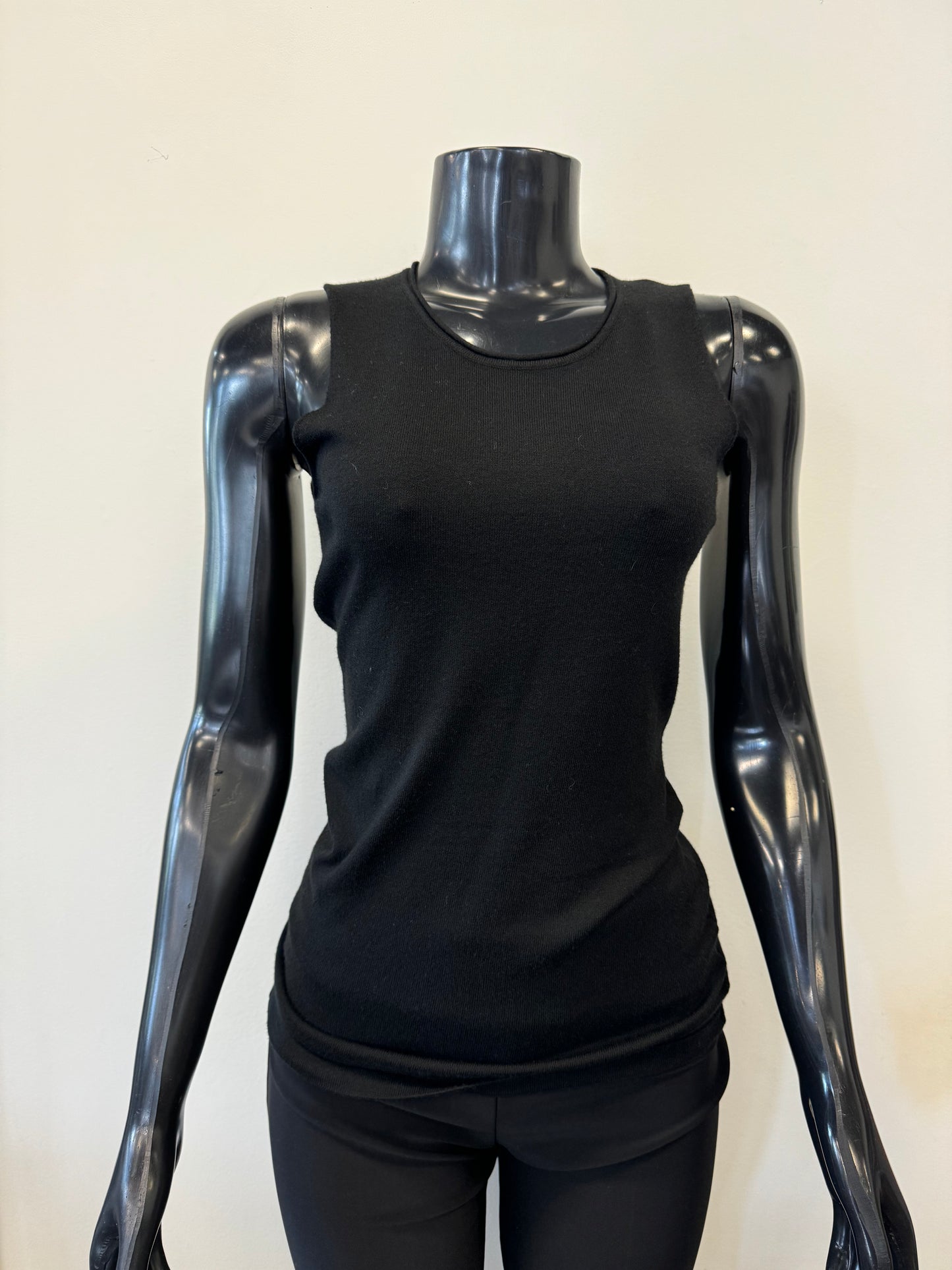 The image features a black mannequin with a glossy finish wearing the Knit Tank Top by ETERNELLE. The background is a plain light beige, providing the piece from Montreal with an elegant and understated setting.