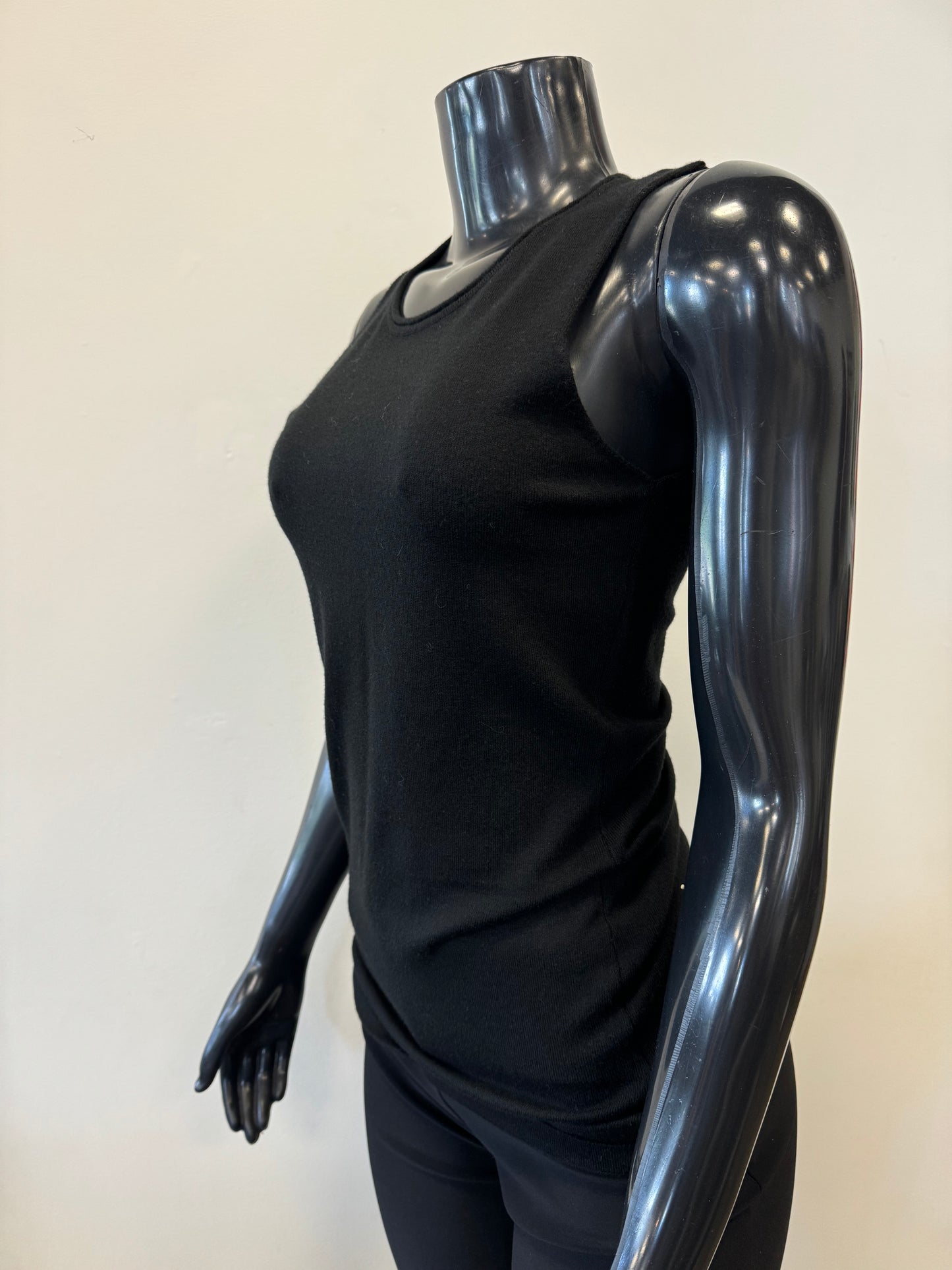 The image features a black mannequin with a glossy finish wearing the Knit Tank Top by ETERNELLE. The background is a plain light beige, providing the piece from Montreal with an elegant and understated setting.