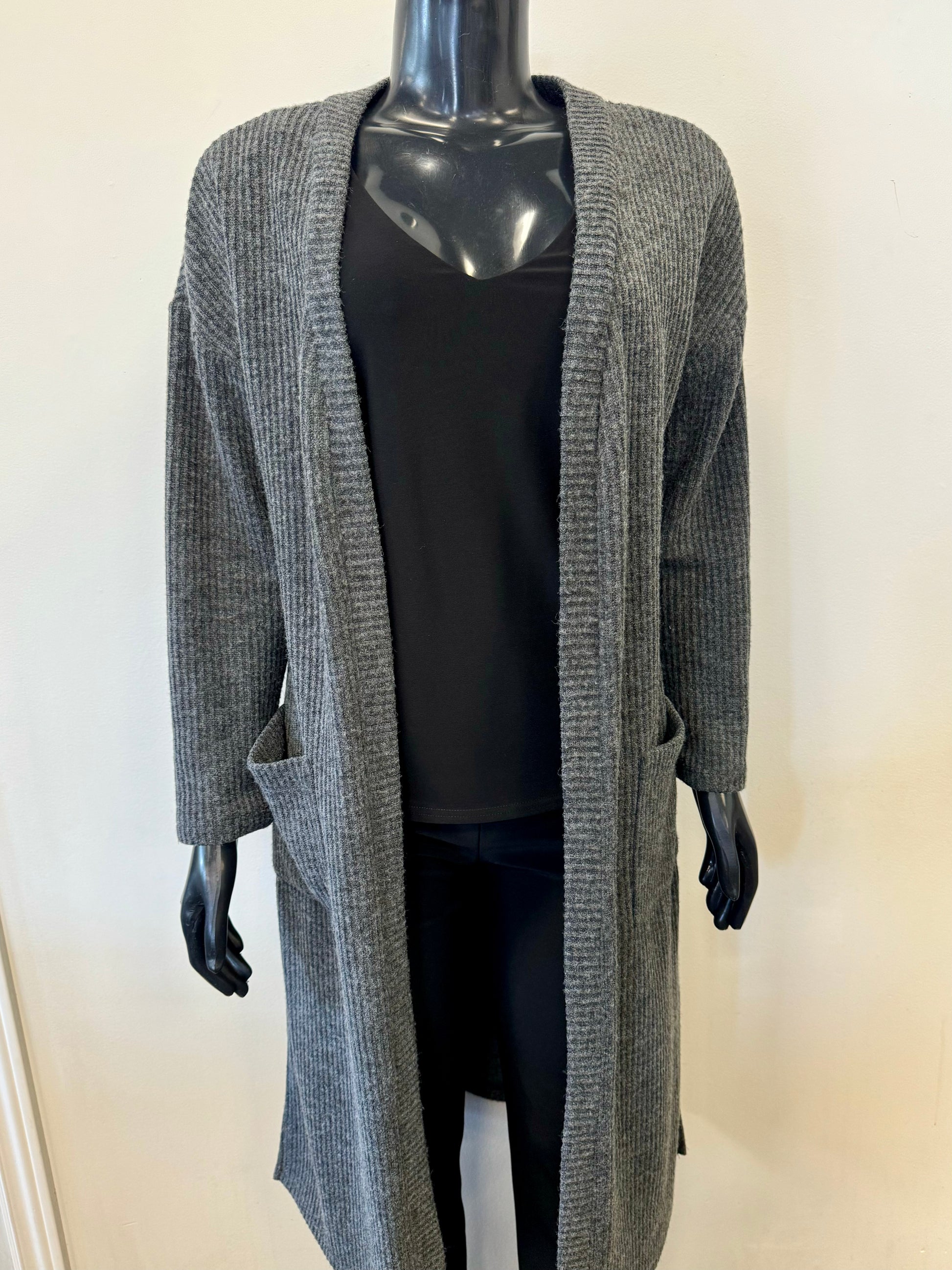 A mannequin dressed in Bali Corp's "Cardigan Grey Winter - Bali 7704" over a black top and black pants. The ribbed cardigan, made in Canada, features two front pockets and is displayed against a plain, light-colored background.