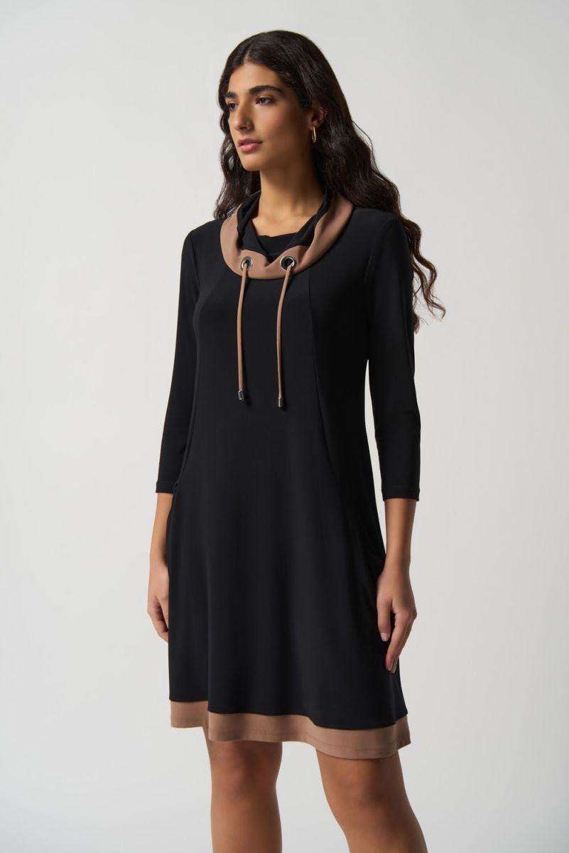 A woman with long, wavy hair wears the Joseph Ribkoff Contrast Trim Dress Style 233035, featuring a shawl collar neckline and brown accents. The dress has three-quarter sleeves and falls just above the knee. Made in Canada, she stands against a plain white background, looking to the side.