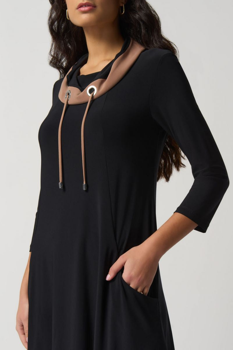 A woman with long, wavy hair wears the Joseph Ribkoff Contrast Trim Dress Style 233035, featuring a shawl collar neckline and brown accents. The dress has three-quarter sleeves and falls just above the knee. Made in Canada, she stands against a plain white background, looking to the side.