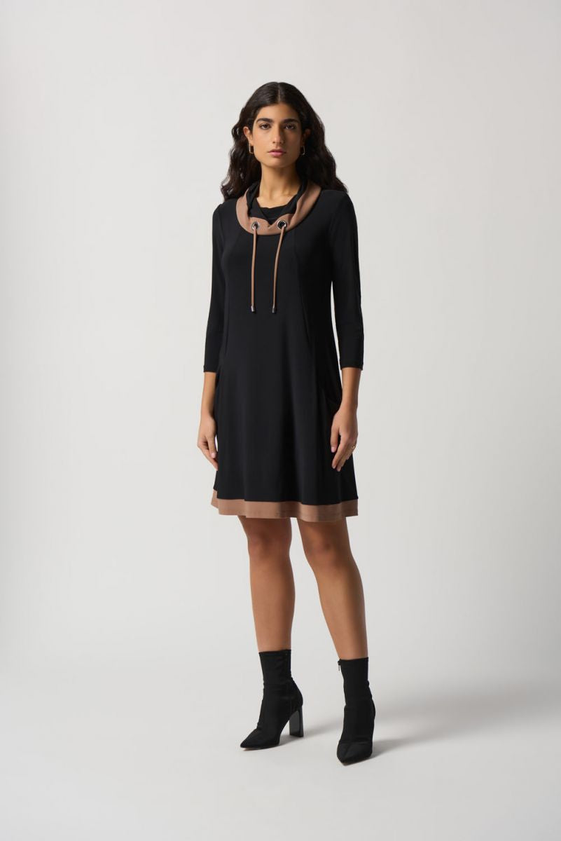 A woman with long, wavy hair wears the Joseph Ribkoff Contrast Trim Dress Style 233035, featuring a shawl collar neckline and brown accents. The dress has three-quarter sleeves and falls just above the knee. Made in Canada, she stands against a plain white background, looking to the side.