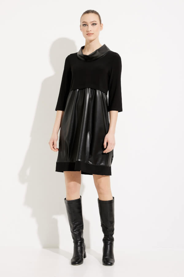 A woman stands against a white background wearing the Joseph Ribkoff Faux Leather Cocoon Dress Style 233091, a black empire waist dress with three-quarter sleeves and a shiny faux-leather material on the lower portion. She pairs the dress with knee-high black boots and has her hair styled in a neat updo.