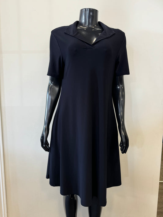 A black mannequin dressed in Bali Corp's Navy Dress 8031, featuring a knee-length, short-sleeve design with a V-neckline and a slightly flared skirt. The mannequin stands against a plain, light-colored background.