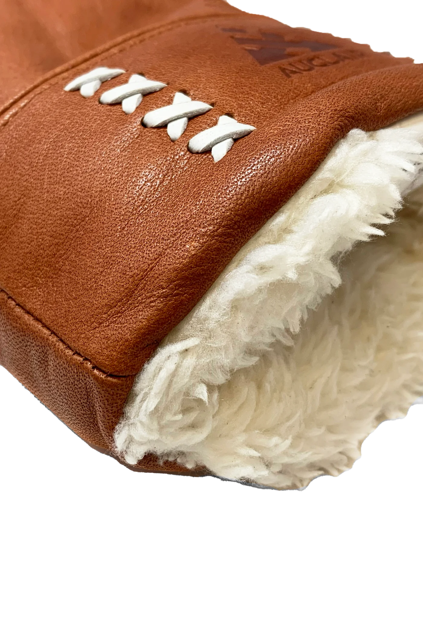 A close-up of the AUCLAIR Anouk Mitts for women showcases the durable brown cow leather with a plush white fur lining at the cuff. White stitching forms an X pattern along the side for added protection. The texture of the leather and the plushness of the fur lining are clearly visible.