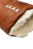A close-up of the AUCLAIR Anouk Mitts for women showcases the durable brown cow leather with a plush white fur lining at the cuff. White stitching forms an X pattern along the side for added protection. The texture of the leather and the plushness of the fur lining are clearly visible.