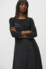 A person with long, straight hair is confidently posing with arms crossed against a plain background. They are wearing the Silky Knit And Jacquard Handkerchief Dress by Joseph Ribkoff, which features an asymmetrical cut and textured pattern on one side. They accessorize with silver bracelets on one wrist.