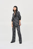 A person with long, straight hair stands against a plain backdrop wearing a matching dark patterned Joseph Ribkoff Tweed Knit Fitted Blazer (243053) and wide-leg pants with a textured design, embodying the elegance of a versatile fashion piece. Their hands are relaxed at their sides as they look slightly to the left with a neutral expression.