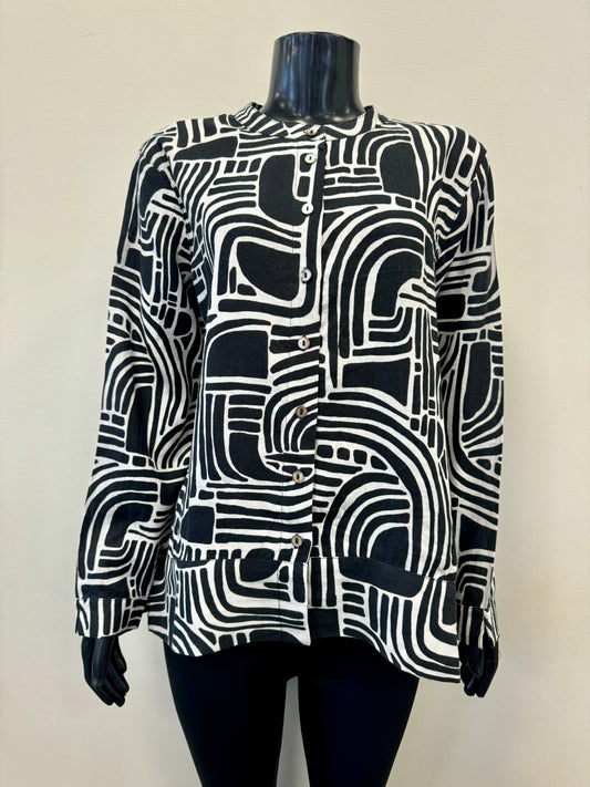 A mannequin sporting the FOIL Summer Days Linen Shirt - FOIL FO7463, showcasing a striking abstract geometric pattern. This black and white long-sleeve button-up, crafted from premium linen, features a labyrinth-like design of curved and straight lines with white buttons down the front. Ideal for your summer wardrobe, it makes a statement against a plain background.