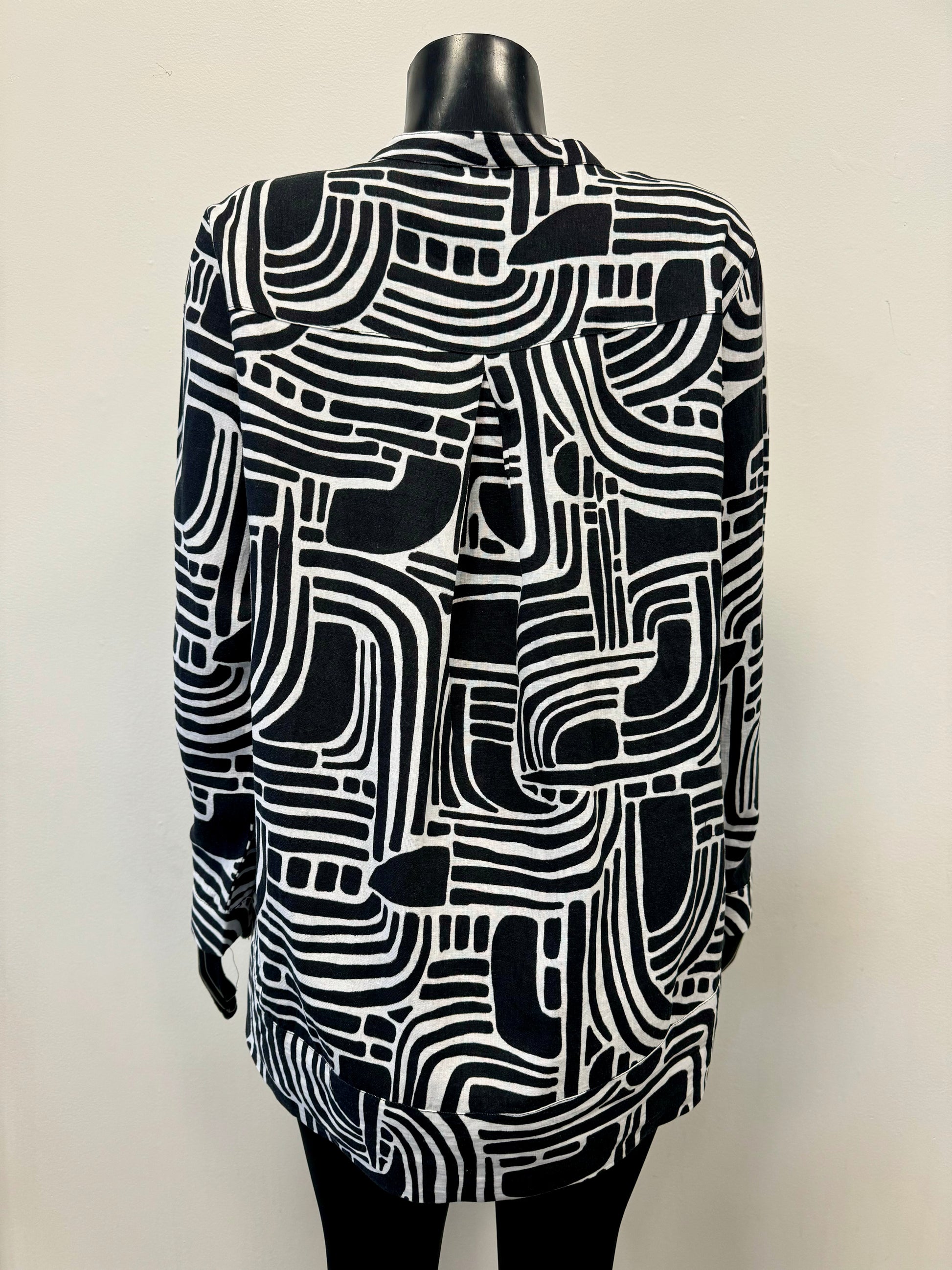 A mannequin sporting the FOIL Summer Days Linen Shirt - FOIL FO7463, showcasing a striking abstract geometric pattern. This black and white long-sleeve button-up, crafted from premium linen, features a labyrinth-like design of curved and straight lines with white buttons down the front. Ideal for your summer wardrobe, it makes a statement against a plain background.