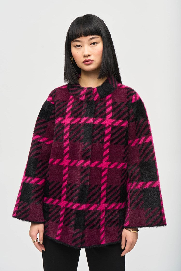 A woman with straight black hair and bangs stands against a plain background. She is wearing the stylish Feather Yarn Jacquard Plaid Jacket 243931 by Joseph Ribkoff, featuring a bold magenta and black checkered pattern. She has a neutral expression, and her arms are relaxed at her sides.