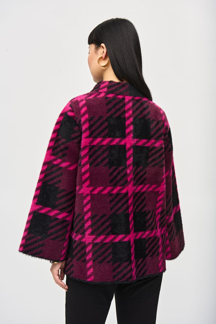 A woman with straight black hair and bangs stands against a plain background. She is wearing the stylish Feather Yarn Jacquard Plaid Jacket 243931 by Joseph Ribkoff, featuring a bold magenta and black checkered pattern. She has a neutral expression, and her arms are relaxed at her sides.