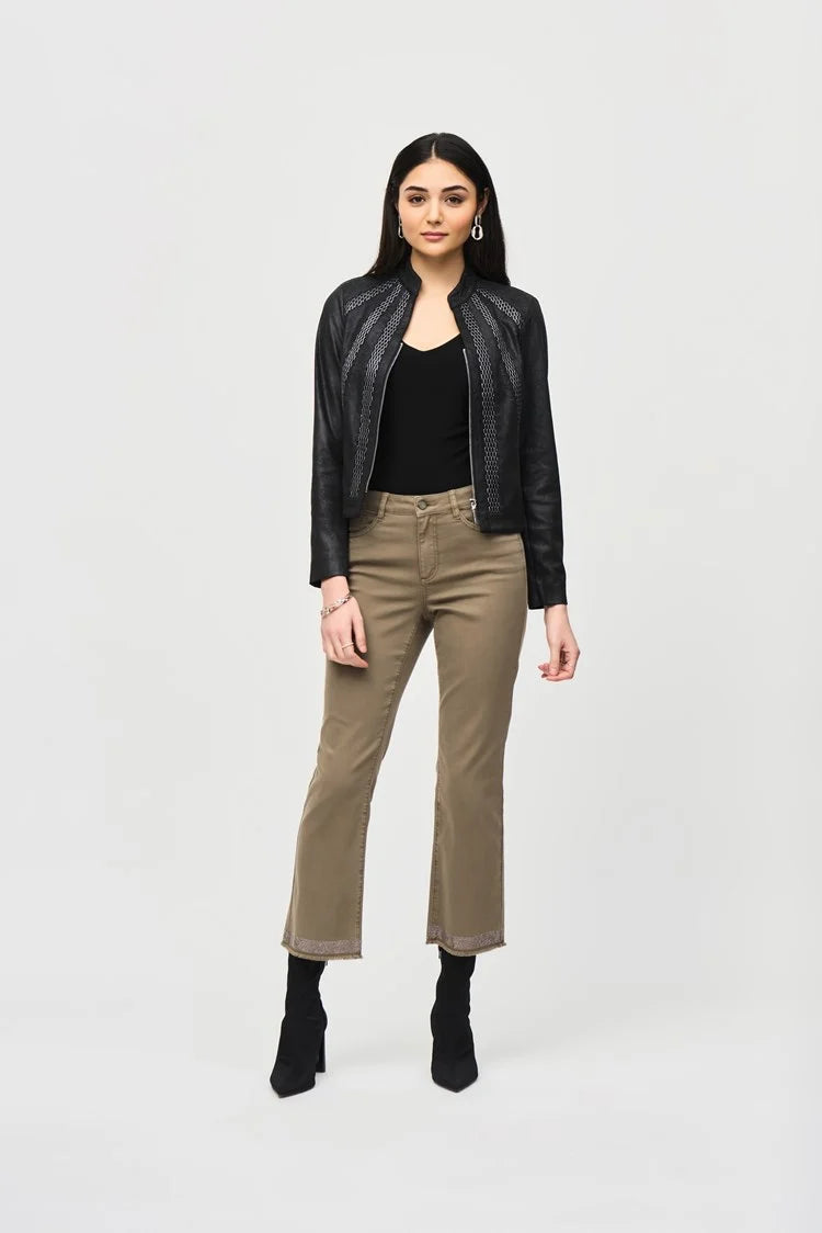 A woman stands against a plain white background, wearing the Joseph Ribkoff Faux Suede Jacket With Metallic Mesh Detail 243972. She pairs it with khaki straight-leg pants that are slightly cropped and black heeled ankle boots. Her long, dark hair cascades down, and she accessorizes with statement earrings.