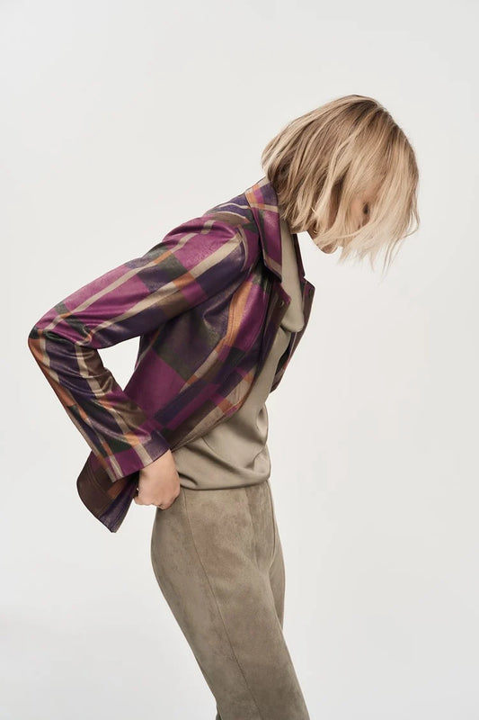 A person with shoulder-length blonde hair is leaning forward slightly while wearing the Foiled Print Faux Suede Jacket 243921 by Joseph Ribkoff over a light-colored top and taupe pants. The background is plain and light-colored, emphasizing the outfit and pose.