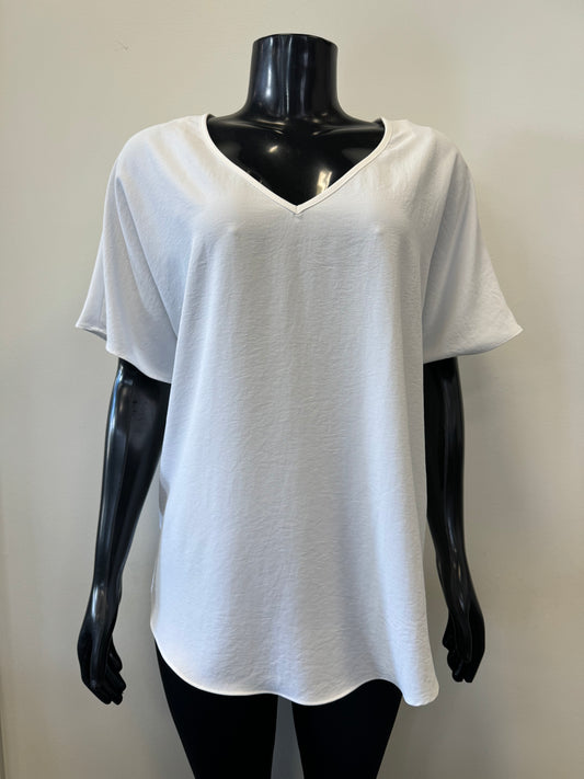 A black mannequin showcases a simple, loose-fitting white V-neck T-shirt with short sleeves and a relaxed fit, known as the Loose V-neck Top Style 231002 by Joseph Ribkoff. The slouchy top is set against a plain, light-colored background.