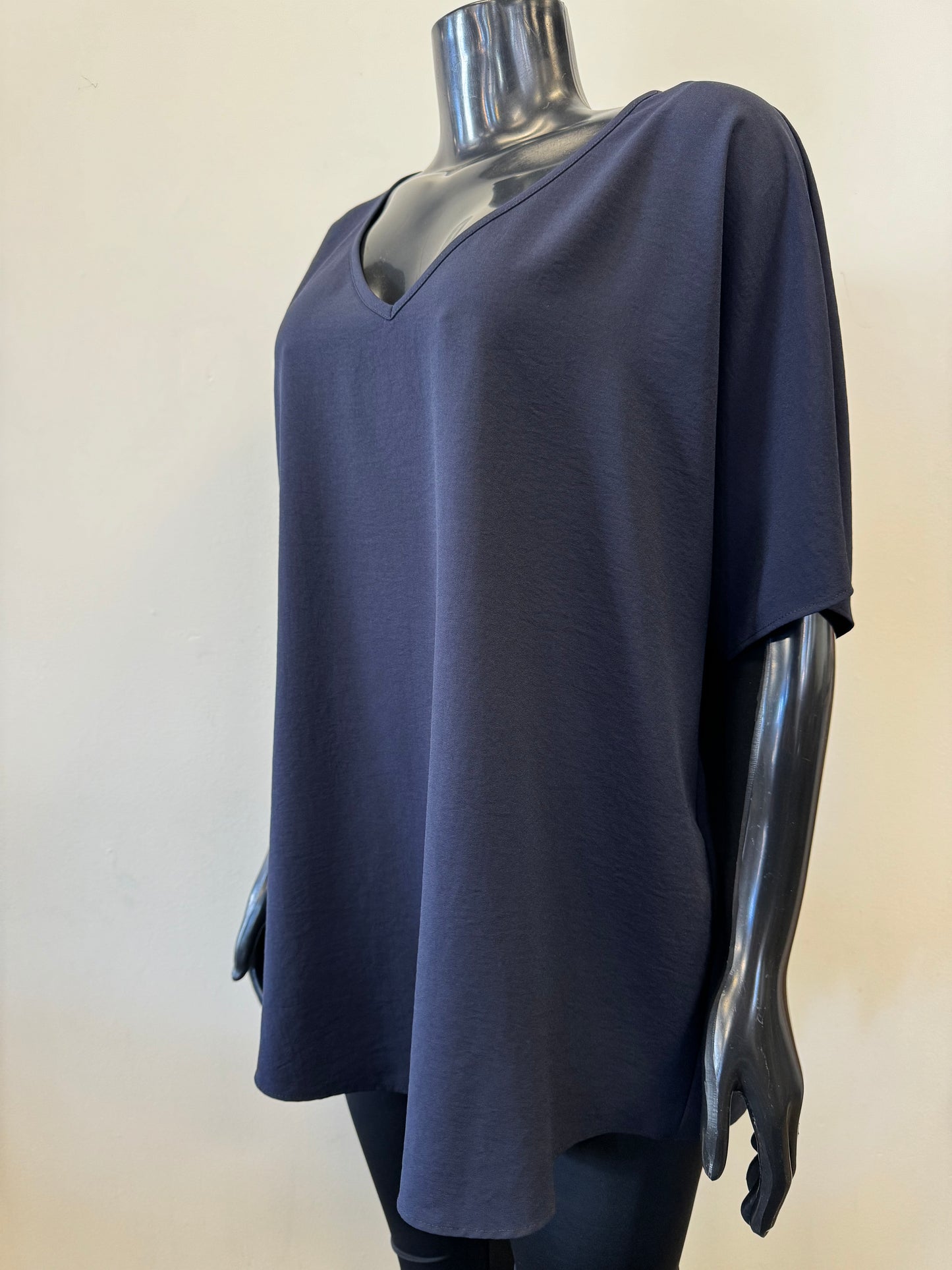 A black mannequin showcases a simple, loose-fitting white V-neck T-shirt with short sleeves and a relaxed fit, known as the Loose V-neck Top Style 231002 by Joseph Ribkoff. The slouchy top is set against a plain, light-colored background.