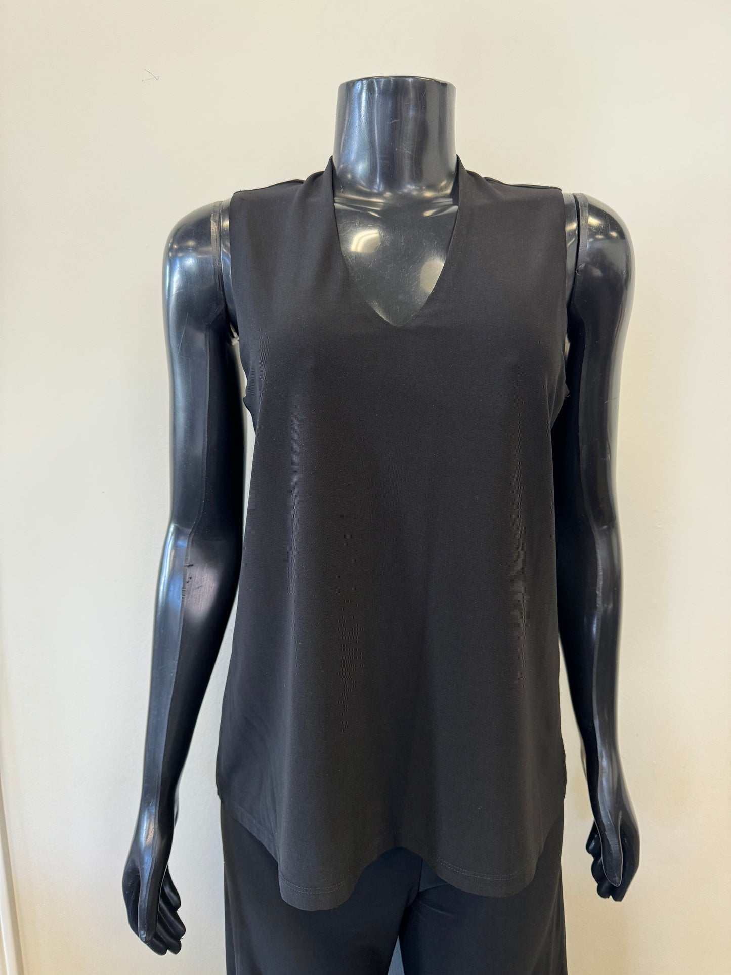 A black mannequin displays a sleeveless, deep V-neck, navy blue Bali Corp Bali Top Sleeveless 8326 paired with black trousers. The versatile top is made in Canada and stands out against the plain, white background.