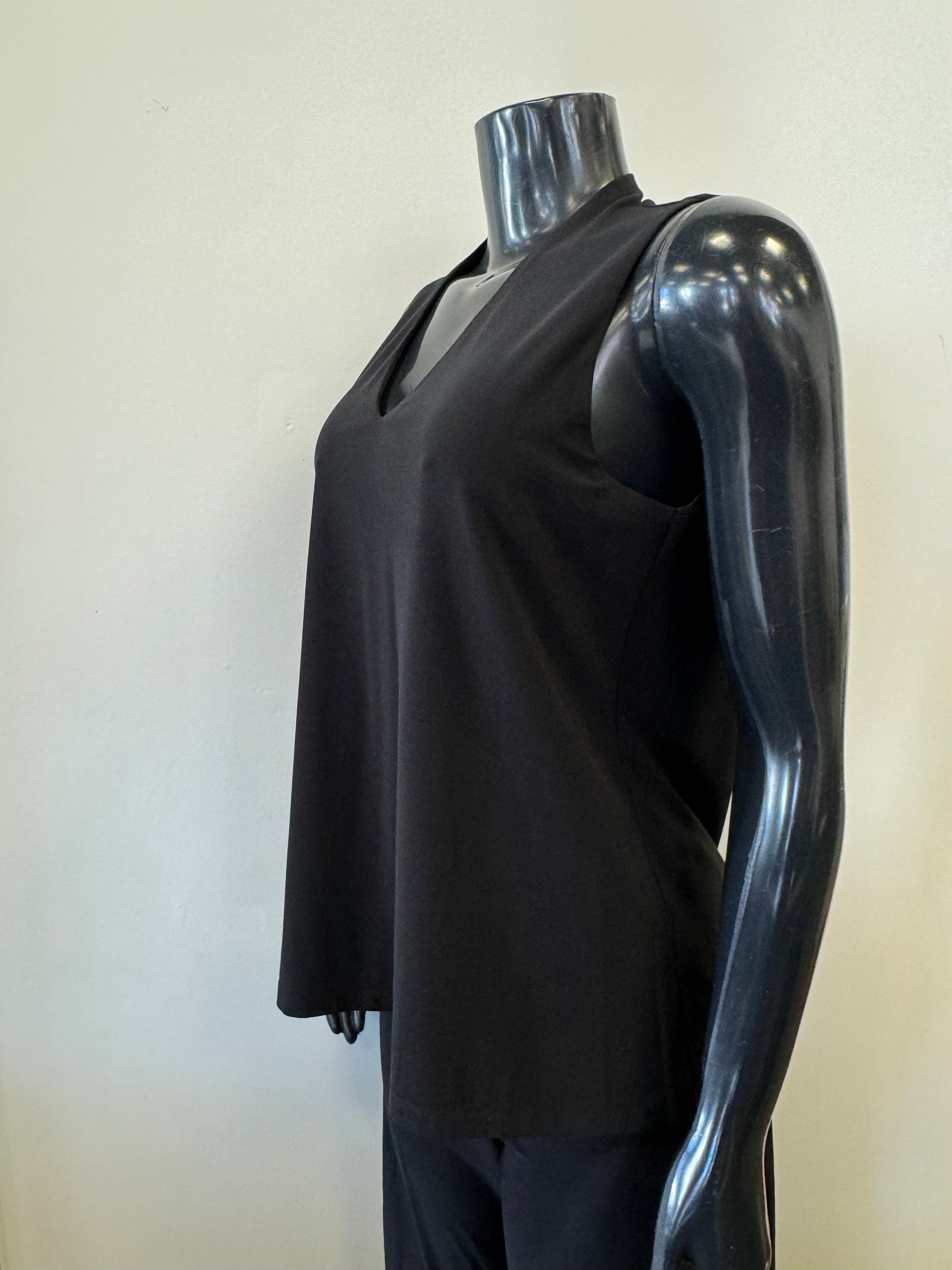 A black mannequin displays a sleeveless, deep V-neck, navy blue Bali Corp Bali Top Sleeveless 8326 paired with black trousers. The versatile top is made in Canada and stands out against the plain, white background.