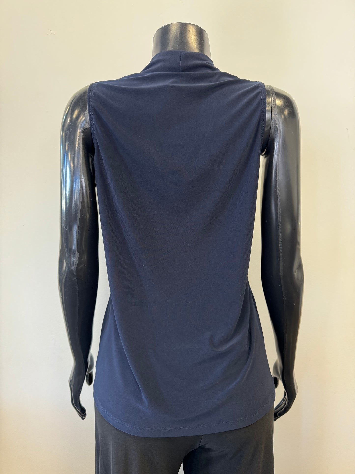 A black mannequin displays a sleeveless, deep V-neck, navy blue Bali Corp Bali Top Sleeveless 8326 paired with black trousers. The versatile top is made in Canada and stands out against the plain, white background.