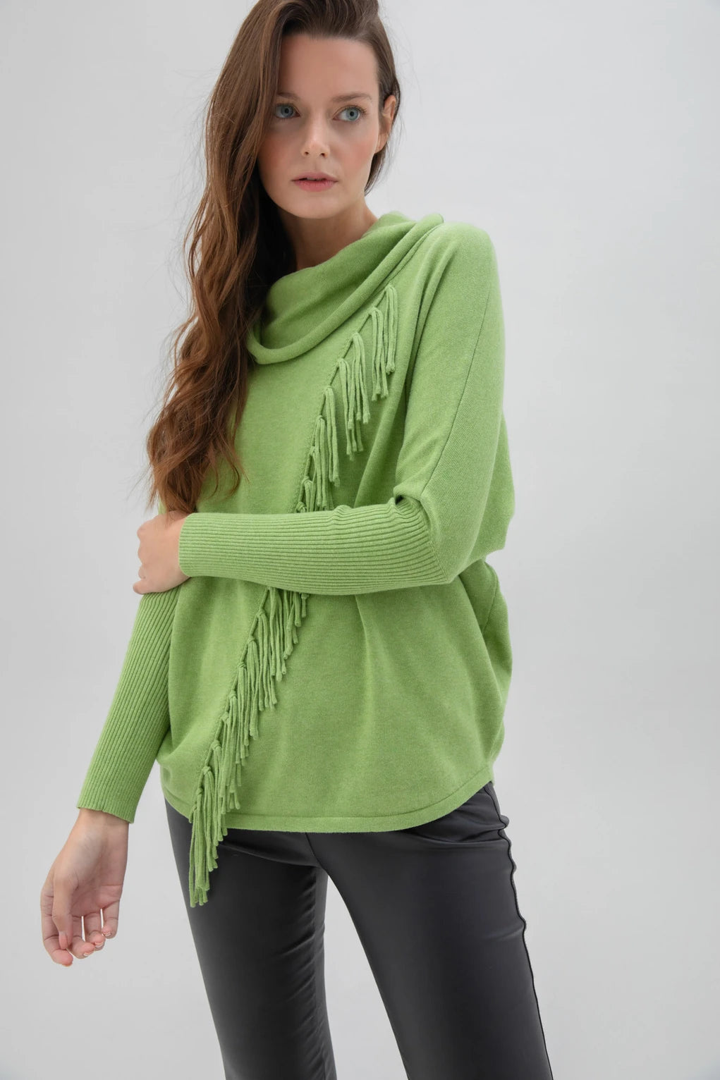 The Marble brand product, Sweater 6373-104 MARBLE, is a white, long-sleeved cotton sweater featuring a cowl neck and decorative fringe detailing that starts from the neckline and runs diagonally across the front. This high-quality sweater has a relaxed fit and ribbed cuffs on the sleeves.