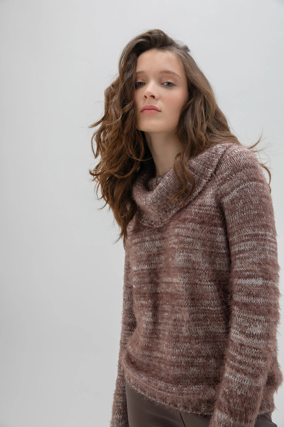 A woman with long, wavy brown hair is wearing a fashionable and cozy Sweater 7544 MARBLE by MARBLE. The fuzzy brown sweater features a stylish cowl neck. She is standing against a plain white background and looking forward with a neutral expression.