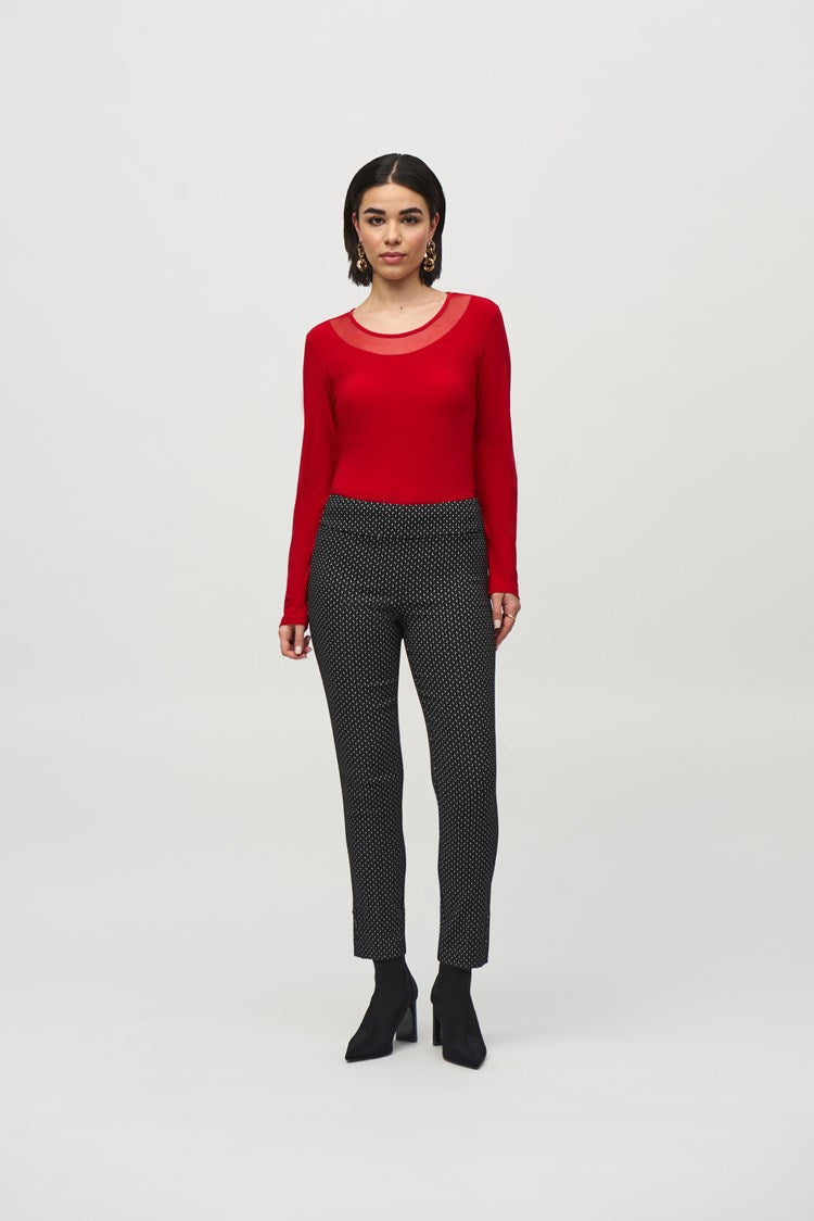 A woman wearing a fitted red long-sleeve top, paired with Joseph Ribkoff's Jacquard Abstract Print Pull-On Pants (style 244140), and ankle-length black boots stands against a plain white background. She has shoulder-length dark hair and is looking directly at the camera with a neutral expression.