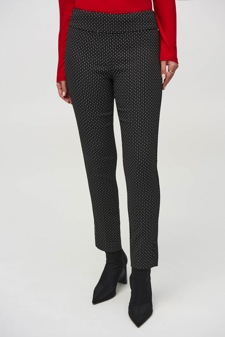 A woman wearing a fitted red long-sleeve top, paired with Joseph Ribkoff's Jacquard Abstract Print Pull-On Pants (style 244140), and ankle-length black boots stands against a plain white background. She has shoulder-length dark hair and is looking directly at the camera with a neutral expression.