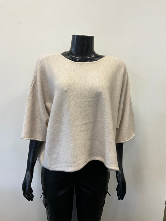 A mannequin dressed in a loose-fitting, light beige Sweater Round Neck - Eternelle made from premium fabrics with three-quarter-length sleeves. The ETERNELLE brand top is paired with black pants. The mannequin stands against a plain, light-colored background.