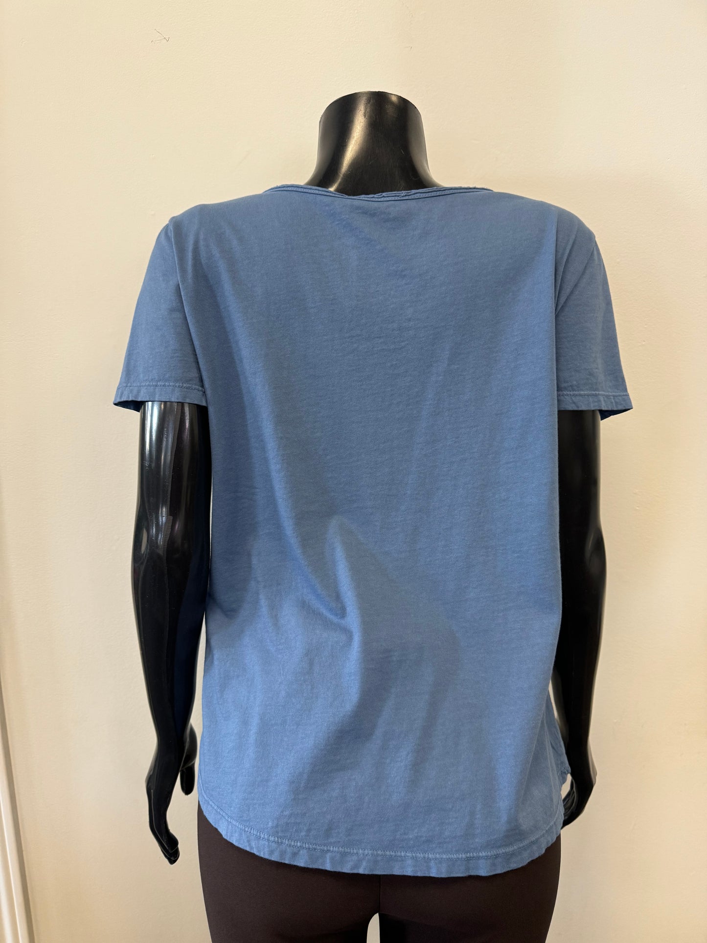 The elegant Femme Fatale Indigo Cotton Top is showcased on a black mannequin. This Italian-made shirt features short sleeves, a notched neckline, and four decorative buttons on one side. It hangs loosely with a slight flare at the bottom against a plain off-white background.