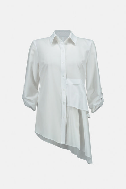 A person with long dark hair is wearing a white Joseph Ribkoff Tiered Asymmetric Hem Blouse Style 233099, which features asymmetric layers on the front and 3/4 sleeves. Paired with black pants adorned with a white grid pattern, this stylish ensemble by Joseph Ribkoff is perfect for an office wardrobe. The background is plain white.