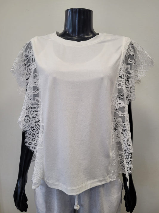 A mannequin displays the Bali Corp Laced Top 8638-Bali Corp, featuring white floral lace, sheer ruffle sleeve details, a round neckline, and a soft, flowy fit. It is styled with black mannequin hands and neck.