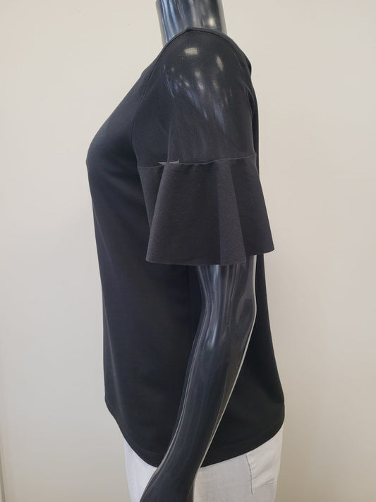 A side view of the TOP 8597-Bali Corp black shirt by Bali Corp, featuring frilly sleeves in viscose-spandex fabric, is shown on a glossy black mannequin against a plain white background.