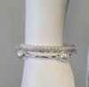 A white mannequin wrist displays the Mimosa 20 Bracelet by Elise accessories, featuring lustrous pearls, sparkling rhinestones, and a thin silver bangle accented with large pearl beads and rhinestones.
