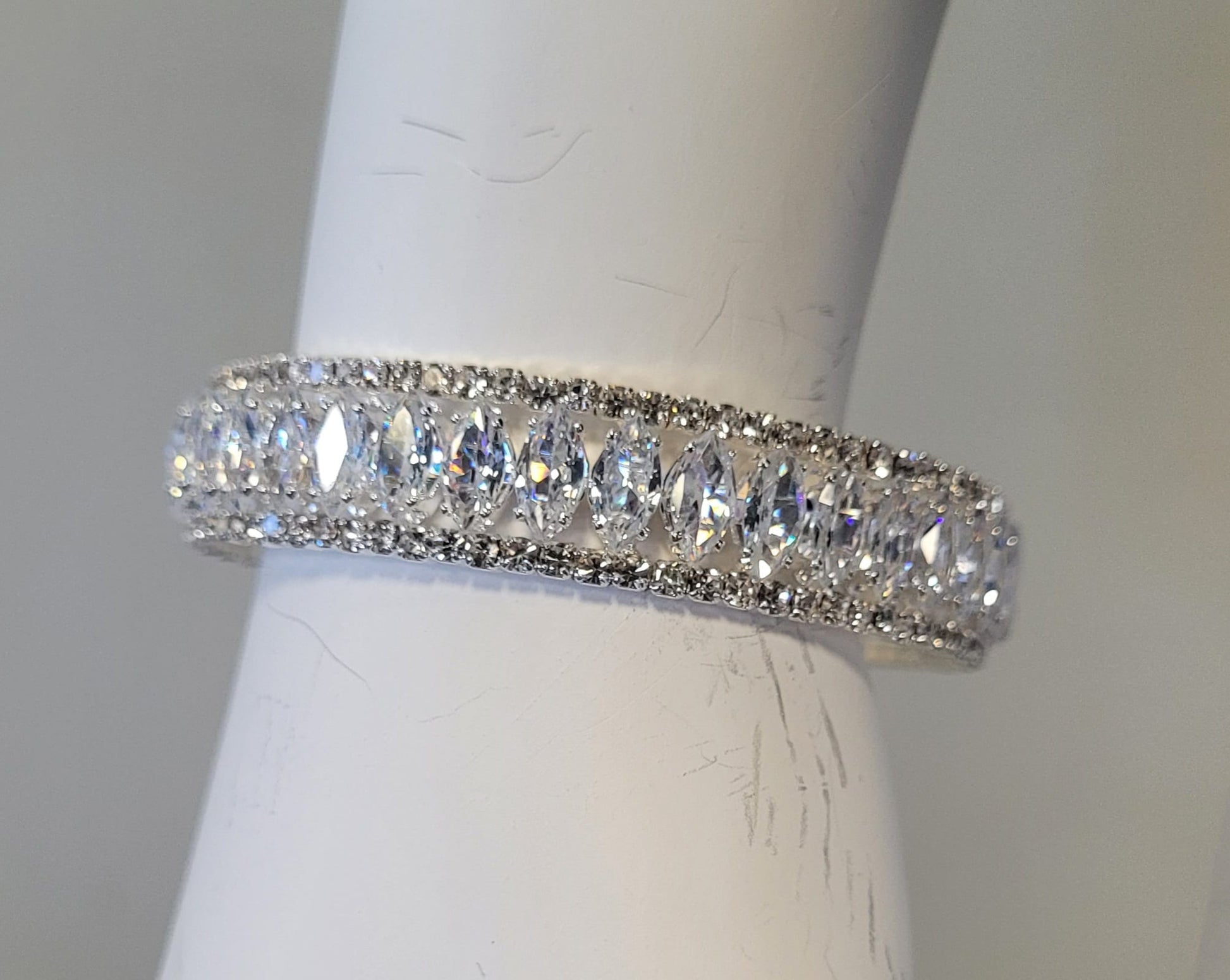The Mimosa 15 Bracelet by Elise Accessories features marquise-cut clear gemstones on memory wire, bordered by smaller round stones, and is shown on a white holder.