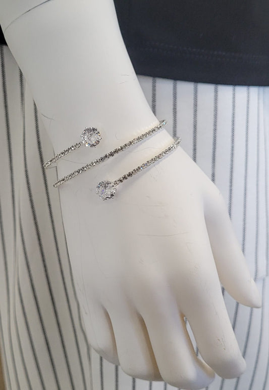 A mannequin hand displays the Elise accessories Mimosa 10 Bracelet, a double coil silver crystal wrap with two round gemstones at each end, set against black and white vertical stripes—ideal for special occasions.